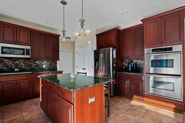 kitchen featuring a breakfast bar area, tasteful backsplash, hanging light fixtures, appliances with stainless steel finishes, and a kitchen island