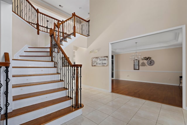 staircase featuring an inviting chandelier, baseboards, ornamental molding, and tile patterned floors