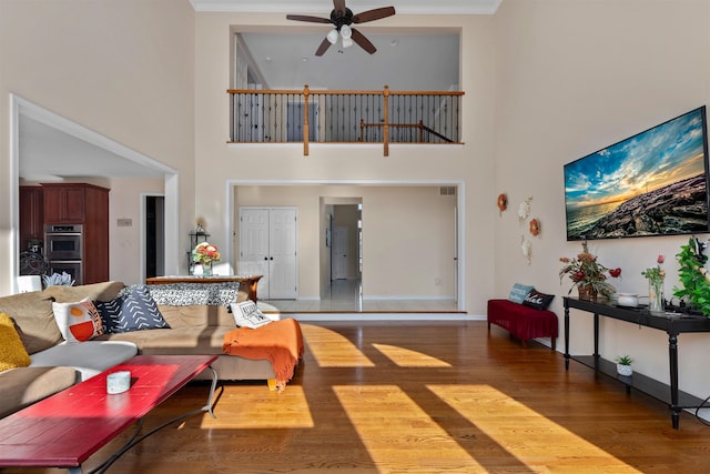 living area featuring ceiling fan, baseboards, and wood finished floors