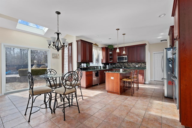 kitchen featuring stainless steel appliances, a kitchen island, hanging light fixtures, backsplash, and a kitchen bar