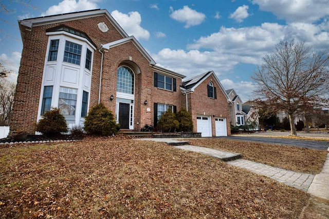 traditional home with brick siding, driveway, and an attached garage