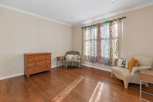 living area with baseboards, ornamental molding, and wood finished floors