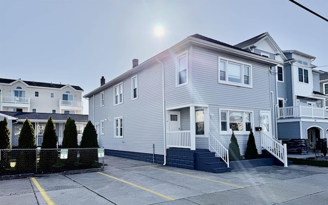 view of front of house with fence, uncovered parking, and a chimney