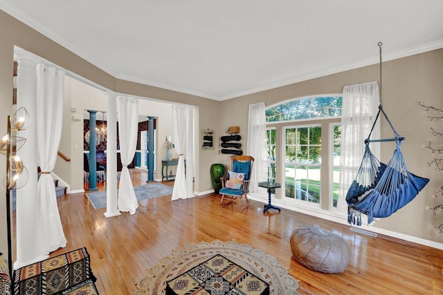 interior space with hardwood / wood-style floors, ornate columns, and crown molding