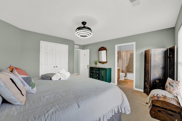 bedroom with a closet, light carpet, and ensuite bath