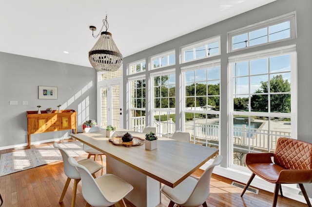 dining space with light hardwood / wood-style floors and a notable chandelier