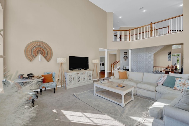 carpeted living room featuring decorative columns, washer / clothes dryer, and a high ceiling