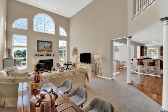 living room featuring carpet flooring, a towering ceiling, and decorative columns