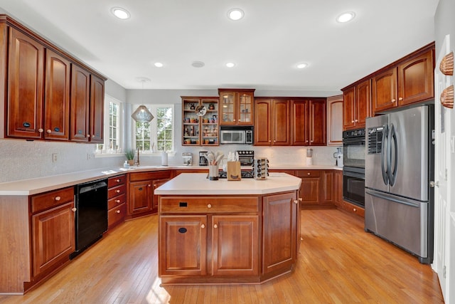 kitchen featuring pendant lighting, black appliances, light hardwood / wood-style flooring, tasteful backsplash, and a kitchen island