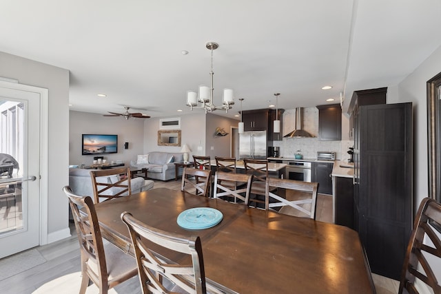 dining area featuring light hardwood / wood-style floors and ceiling fan with notable chandelier