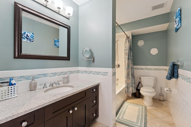 full bathroom with vanity, tile patterned floors, toilet, tile walls, and shower / tub combo