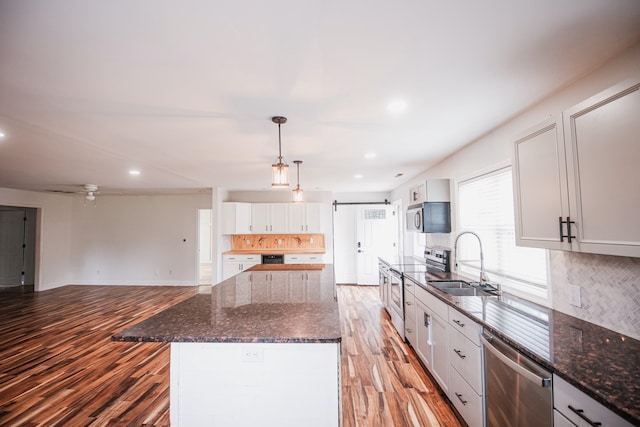 kitchen featuring appliances with stainless steel finishes, backsplash, sink, white cabinetry, and hanging light fixtures