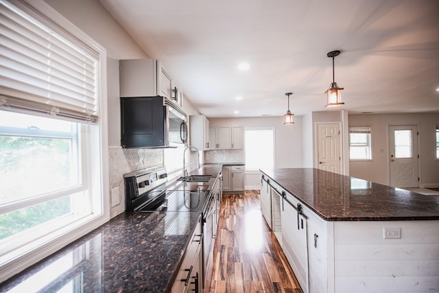 kitchen featuring backsplash, sink, hanging light fixtures, appliances with stainless steel finishes, and a kitchen island