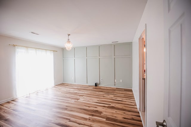 unfurnished bedroom featuring a closet, an inviting chandelier, and light hardwood / wood-style flooring