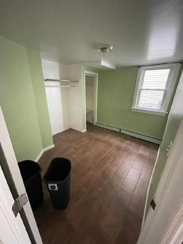 unfurnished bedroom featuring a closet, dark hardwood / wood-style floors, and a baseboard heating unit