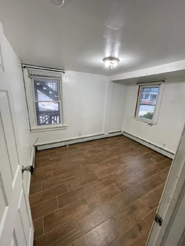 basement featuring dark hardwood / wood-style flooring and a baseboard heating unit