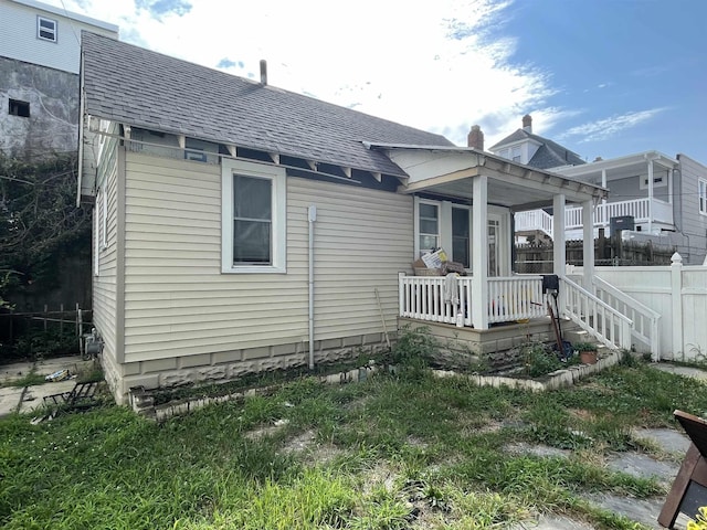 rear view of property featuring covered porch