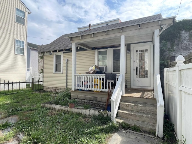 view of exterior entry featuring a porch and a lawn