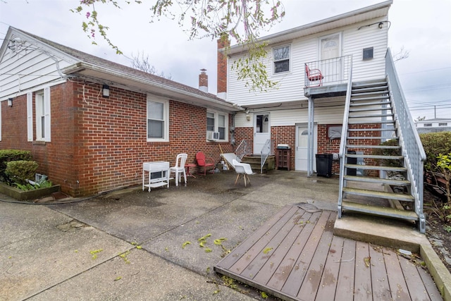 rear view of house with brick siding, a patio, a chimney, and stairway