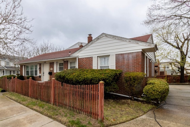 bungalow-style home featuring a chimney, brick siding, and fence private yard