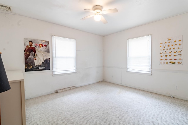 carpeted spare room featuring a ceiling fan, baseboards, a healthy amount of sunlight, and visible vents