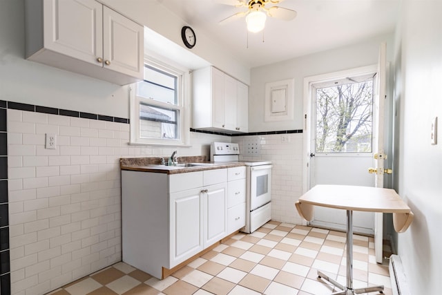 kitchen with white cabinets, a baseboard heating unit, a sink, tile walls, and white electric range