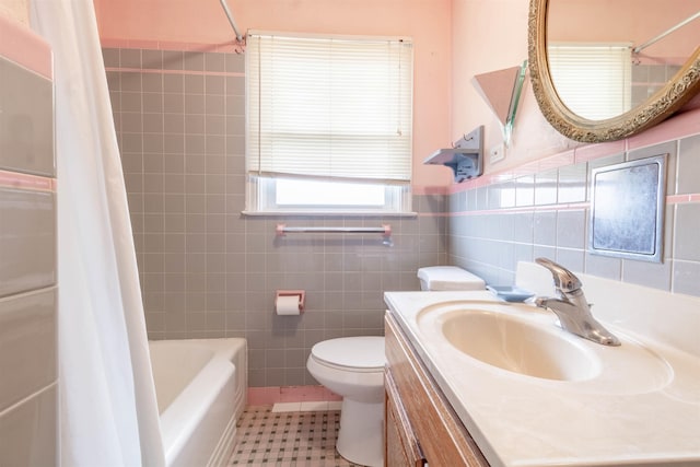 bathroom featuring tile patterned floors, toilet, tile walls, wainscoting, and shower / bathtub combination with curtain