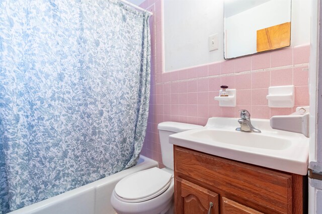 full bathroom featuring tile walls, shower / tub combo with curtain, vanity, and toilet
