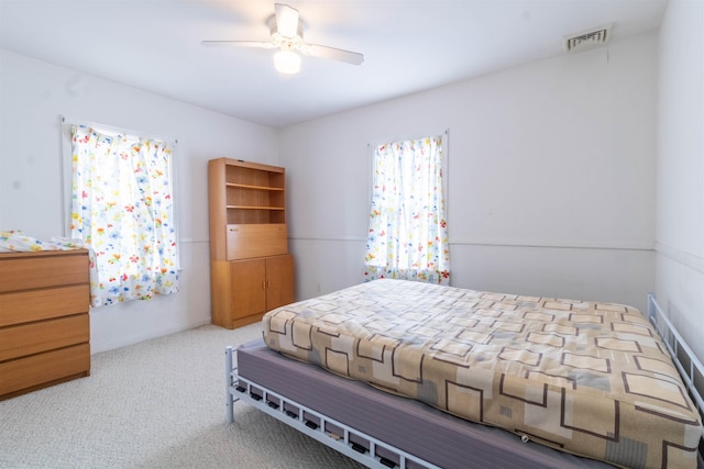 bedroom featuring a ceiling fan, visible vents, and carpet