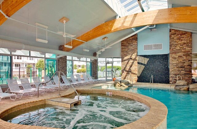 community pool featuring an indoor in ground hot tub, a patio area, and ceiling fan