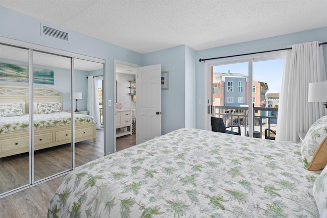 bedroom featuring a textured ceiling, visible vents, wood finished floors, access to outside, and a closet