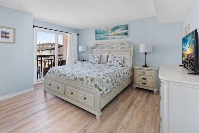 bedroom featuring light wood-type flooring, baseboards, a textured ceiling, and access to exterior