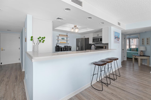 kitchen featuring light wood finished floors, visible vents, and appliances with stainless steel finishes