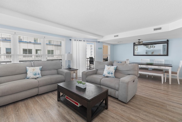 living room featuring visible vents, a textured ceiling, and light wood-style floors