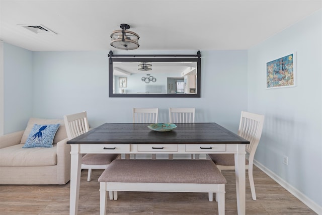 dining space with baseboards, wood finished floors, and visible vents