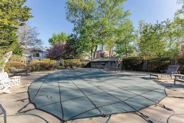view of pool featuring an outdoor structure, fence, a shed, a fenced in pool, and a patio area