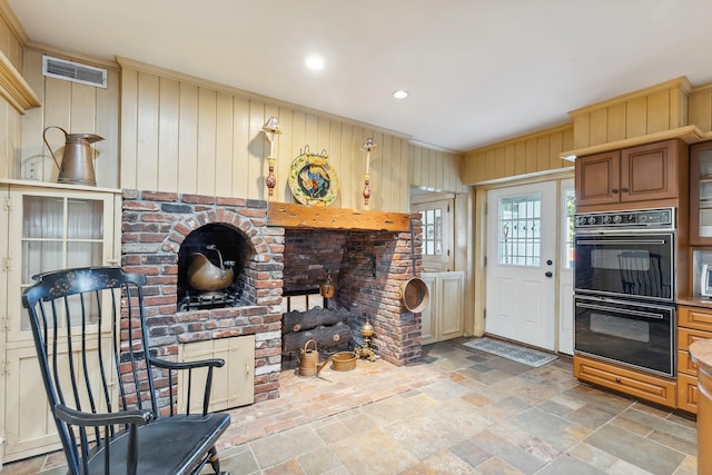 interior space featuring dobule oven black, wood walls, visible vents, stone tile flooring, and recessed lighting