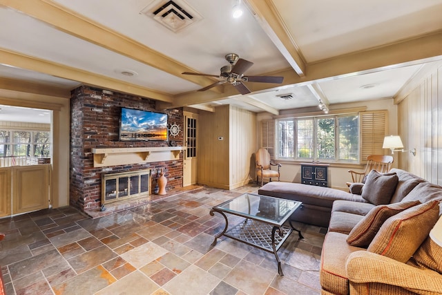 living area featuring beamed ceiling, visible vents, plenty of natural light, and stone tile flooring