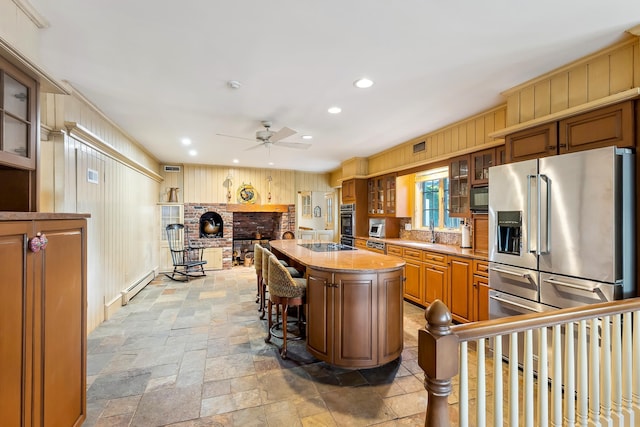 kitchen featuring stone tile floors, ceiling fan, recessed lighting, a baseboard heating unit, and black appliances