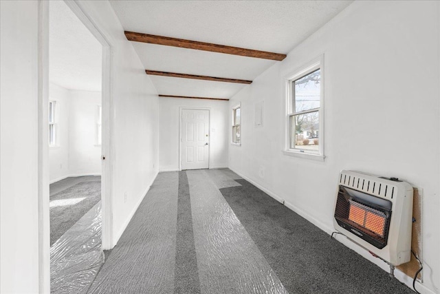 hallway with heating unit, beam ceiling, carpet floors, and a textured ceiling