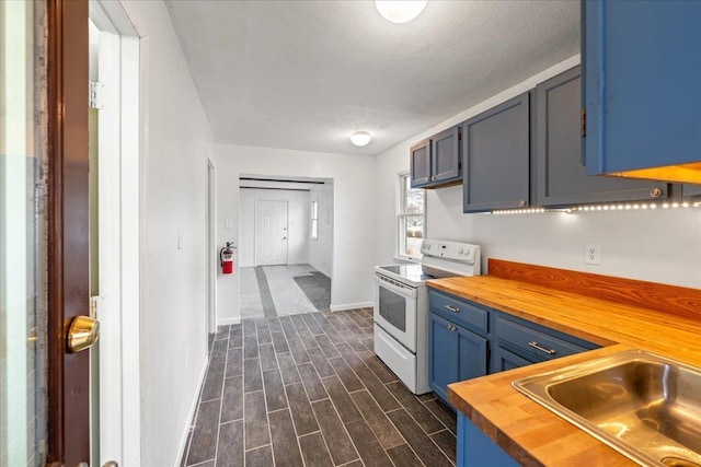 kitchen featuring wood counters, blue cabinets, sink, electric range, and a textured ceiling