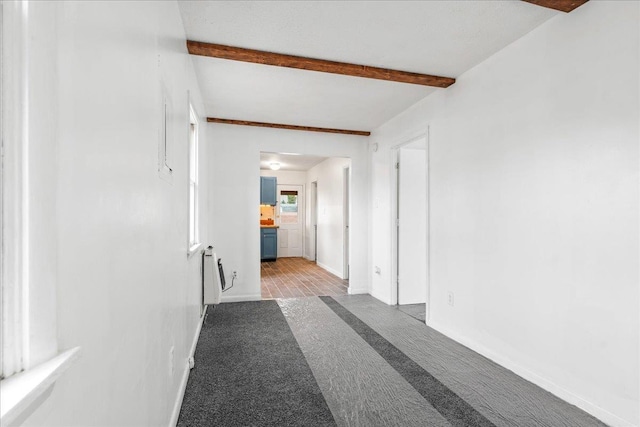 hall with carpet floors, beam ceiling, and radiator heating unit