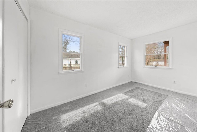 carpeted empty room featuring a textured ceiling