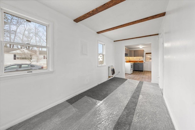 interior space with beamed ceiling, a healthy amount of sunlight, and heating unit