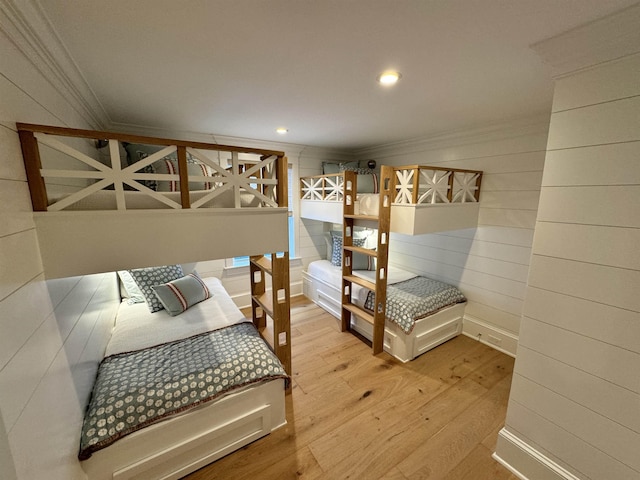 bedroom with wooden walls, ornamental molding, and hardwood / wood-style flooring