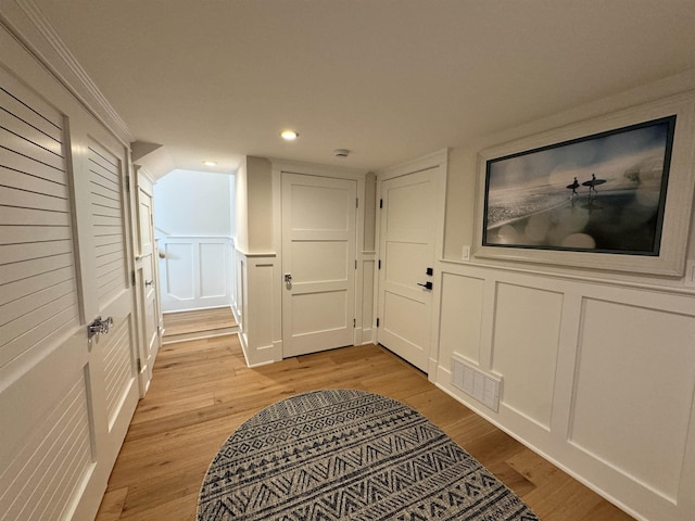 corridor featuring light wood-type flooring and ornamental molding