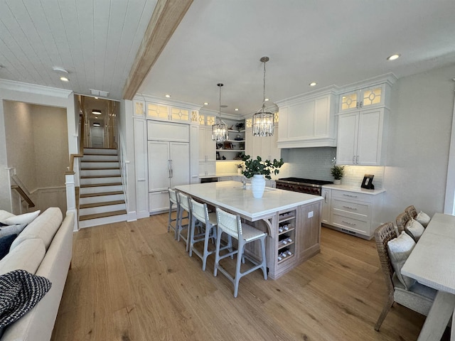 kitchen featuring beam ceiling, paneled fridge, a kitchen island, pendant lighting, and white cabinets