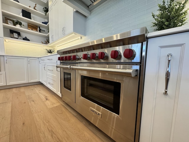 kitchen featuring decorative backsplash, light hardwood / wood-style flooring, white cabinets, and double oven range