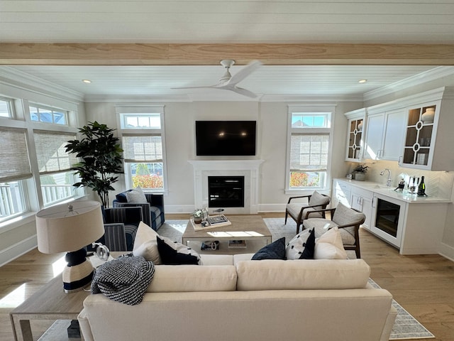 living room with crown molding, sink, ceiling fan, light hardwood / wood-style floors, and beverage cooler