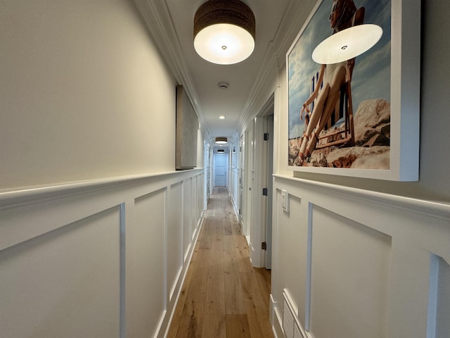 corridor with light hardwood / wood-style flooring and ornamental molding